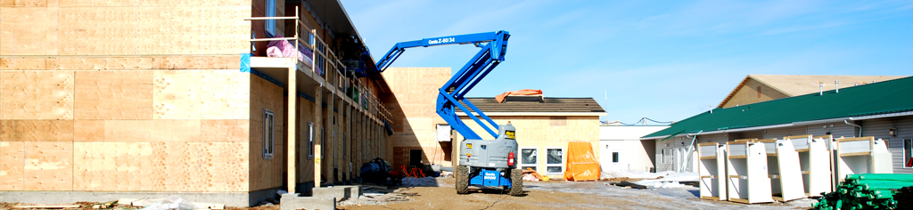 Workers installing a roof onto a pre-fabricated metal building